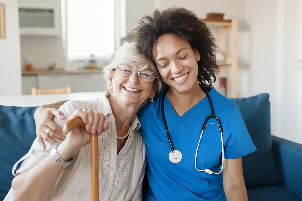 An elderly woman hugging her caregiver after discussing options for respite care in a senior living community.